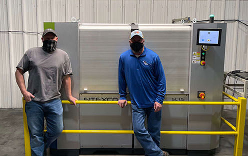 two men standing in front of a roll cleaning machine